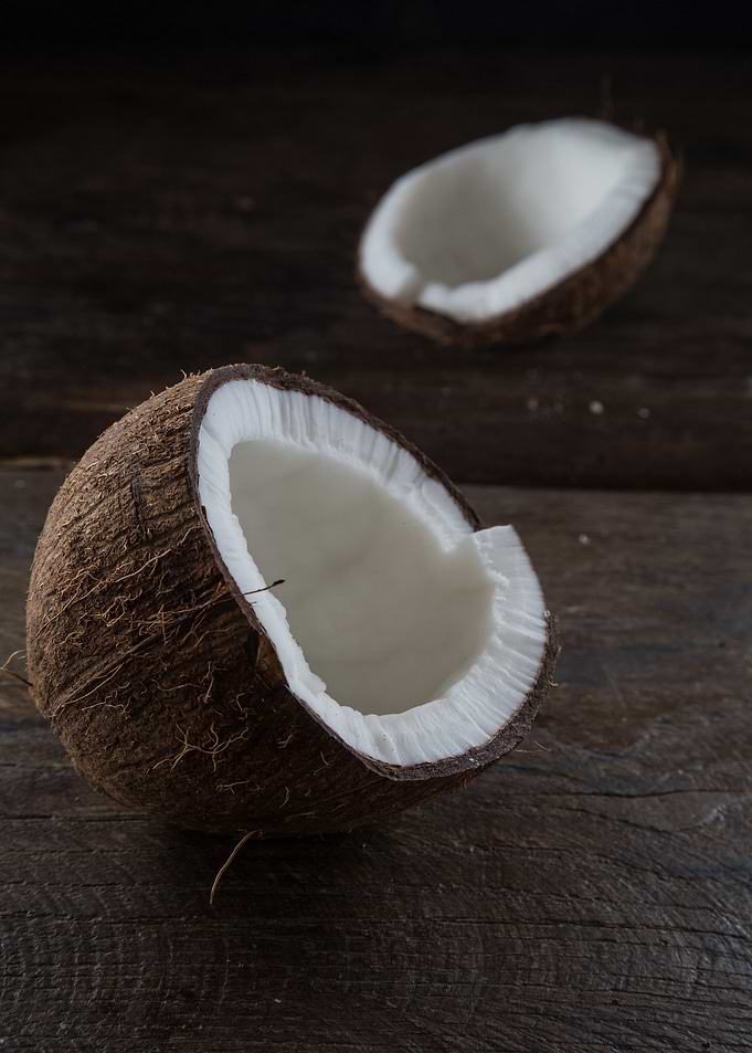 Halved Coconuts on Wooden Surface